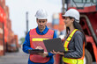 © ultramansk - Two logistics workers man and woman discuss operations at a busy shipping container yard.