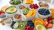 © Hammad - Collection of fresh healthy food ingredients in white ceramic bowls on a bright white background featuring avocado, sliced kiwi, orange, blueberries, raspberries, and organic seeds.