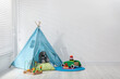 © New Africa - Wigwam, toys and pillows near white wall in child's room, space for text