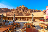 AlUla Old Town framed by mud-brick houses and rugged desert mountains, with AlUla Fort above historic Saudi landscape under a clear blue sky, rich in heritage and texture in Saudi Arabia