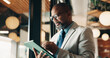 © peopleimages.com - Businessman, glasses and research with tablet in cafe, private wealth attorney and will draft on web. Black person, estate planning and mature lawyer with tech for project or remote work in office