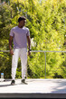 © wavebreak3 - African American man standing on deck looking left, wearing tee and sweatpants, bottle by railing