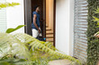 © wavebreak3 - African American man wearing sleeveless navy hoodie entering home at doorway carrying black duffel