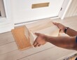© abror - Hands holding cardboard parcel at front doorstep