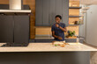 © wavebreak3 - African American male preparing meal in modern kitchen on marble island with bowls, grater