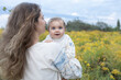 © Anna - young mother with with loose hair holds a charming baby girl in her arms, both dressed in traditional embroidered blouses. We are Ukrainians. Mother's Day. Independence Day. love and support