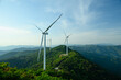 © BananaShot - Wind Turbine Farm on a Forested Mountain Ridge at Golden Hour. Wind turbines generate clean renewable energy.