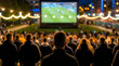 © Hridoy - Crowd of people watching a football match on a large outdoor screen at night