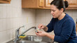 © Xenia - Woman cleaning faucet aerator with a brush in the kitchen. Home plumbing maintenance and repair theme