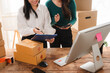 © Kritdanai - Packaging for Success: Two women work together to prepare packages for shipment, surrounded by cardboard boxes and office supplies.