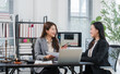 © Kritdanai - Legal Consultation in Office: Two professional women, one likely a lawyer and the other a client, are engaged in a discussion at a desk in a well-lit office.