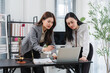 © Kritdanai - Legal Partnership: Two female legal professionals collaborating intently in an office setting, examining documents and a laptop screen, surrounded by legal books and a gavel.
