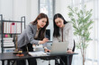 © Kritdanai - Lawyer Collaboration: Two female lawyers intently review a case file on a laptop in their modern office, illuminated by natural light.