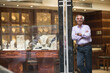 © .shock - Middle Eastern jewelry shop owner standing by display as couple shops for wedding rings with family