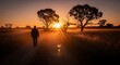 © Samsu - Silhouette of a man walking alone on a dusty path towards a golden sunset.