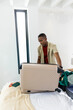© wavebreak3 - African American man leaning and packing suitcase on bed in bright white room with sunglasses