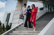 © qunica.com - Three business professionals walk down outdoor steps while reviewing documents and digital devices. Colleagues discuss work and check a tablet and folders as they descend modern office stairs.