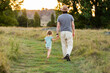 © Austockphoto - Dad on walk with young daughter walking away down grassy path in recreational area
