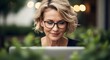 © ArtSync Studio - Mature Woman with Short Blonde Hair Wearing Glasses Working on Laptop Outdoors