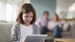 © Firadoaw - young girl using wall mounted smart home tablet while family relaxing in background
