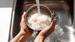 © photo for everything - Close-up of hands prepare food, wash rice in metal bowl under running water with clean fresh water in a kitchen sink for cooking meal