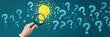 © feri - Hand holding magnifying glass over glowing idea bulb amidst question marks