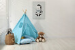 © New Africa - Wigwam, toys and pillows near white wall in child's room, space for text