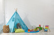 © New Africa - Wigwam, toys and pillows near white wall in child's room
