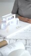 © rogerphoto - Architects discussing modern building design with 3d model and blueprints during planning meeting focused on innovation, teamwork and sustainable construction solutions, close up