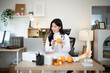 © Stella 16 - Asian Female Nutritionist Doctor Holding Orange During Online Video Consultation with Laptop, ideal for tele health and wellness campaigns