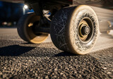 Close-up view of skateboard wheels on asphalt, showing wear and tear under evening light.
