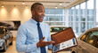 © Vyatcheslav - Excited car salesman presenting a document folder in a dealership. Professional automotive sales consultant
