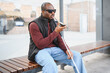 © Serhii - Blind african american man using smartphone at bus stop