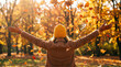 © Pedro Fiuza - Joyful woman in brown coat and yellow hat throwing autumn leaves in the air with arms outstretched in a park during golden hour