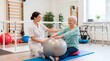 © Стивен Щиров - Physical therapist assisting elderly woman with exercise ball in rehabilitation clinic
