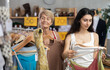 © JackF - Fashionista girl with senior mother near showcase examine goods, buying something summer clothes . Off line clothing store from retailer. Buyer browsing through apparel on display rack. ...