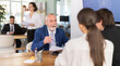 © JackF - Elderly male bank employee at desk with laptop and discussing with young couple customers