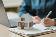 © Garun Studios - Real estate mortgage and property purchase concept with house model, contract documents, and key symbolizing home ownership, financing, and legal agreement.