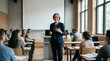 © Alva - A smiling female professor delivers a lecture to a diverse group of students in a modern university classroom with a large projection screen and natural light.