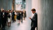 © Selvi - Young man in business attire standing against a modern textured wall while looking at his smartphone in a busy urban environment