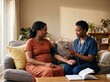 © Ryzhkov - Pregnant Black woman sitting on a sofa during a midwife home visit for blood pressure checkup, medical support, maternity healthcare and feminine wellness campaigns