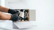 © Nataly - Unboxing product with hands wearing gloves holds stainless steel container from delivery box. Unboxing process features packaging materials and contents in bright workspace.