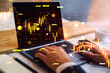 © Who is Danny - Business trader working on laptop with glowing financial charts and digital market indicators overlaid on office desk background in abstract style.