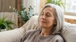 © Iuliia - Mature woman resting on sofa with eyes closed. Senior lady relaxing at home living room. Peaceful lifestyle and mental wellness concept. Serene aging, calm meditation and quiet time.