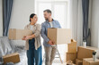 © Serhii - Couple moving into new home carrying cardboard boxes