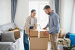 © Serhii - Couple moving into new home carrying cardboard boxes