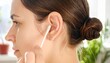 © Cyan Creative - Woman inserting white earbud into her ear with hand