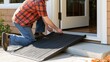 © TAlex - Man installing portable wheelchair threshold ramp at home entrance