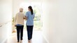 © Nataly - Senior care with nurse assisting elderly woman walking towards garden light. Senior care includes gentle support through hallway while providing companionship and comfort.