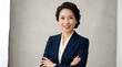 © Wattana - A woman in a professional suit standing in front of a plain background.